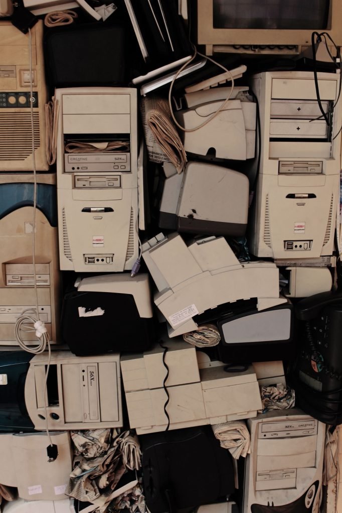 A dense stack of obsolete computer and electronics hardware filling a back room wall
