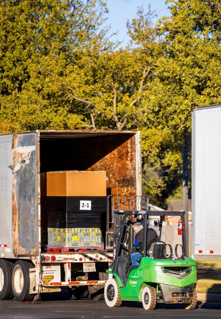 A forklift loading a pallet into the back of a freight trailer