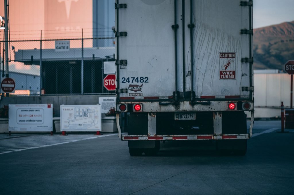 The rear of a freight trailer pulling away from an industrial facility gate