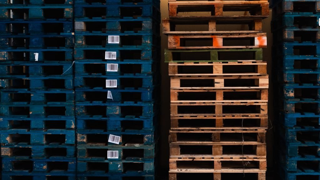 Stacks of wooden and plastic shipping pallets with barcode labels