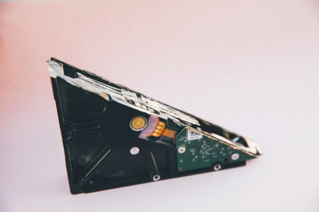 A hard drive opened up with its internal platter and board exposed