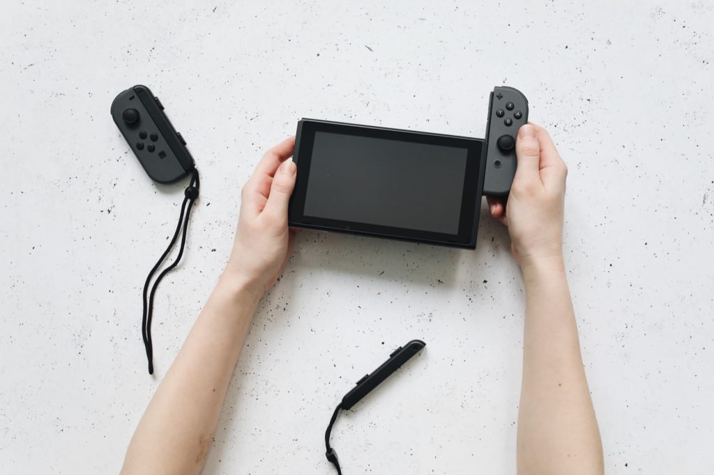 Hands holding a Nintendo Switch with a Joy-Con controller removed