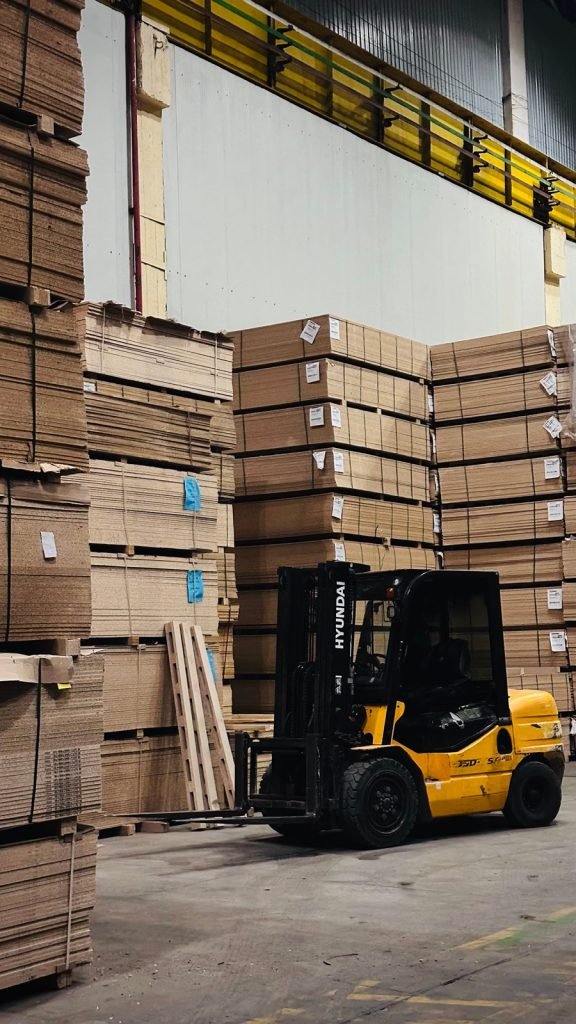 A forklift moving stacked cartons through a high-bay warehouse